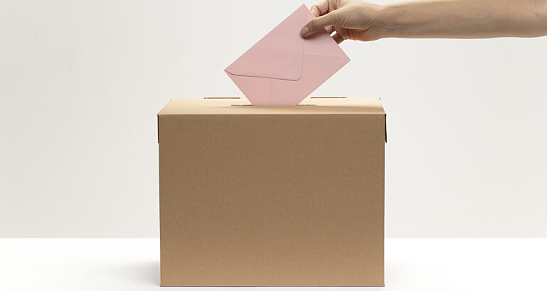 Hand Puts Pink Envelope Into Vote Box